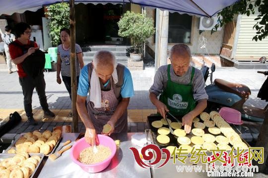 图为老哥俩在街边自制“土月饼”。　张远 摄